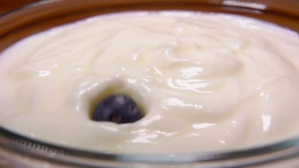 Cereal with blueberries and raspberries falling into bowl with the yogurt — Stock Video