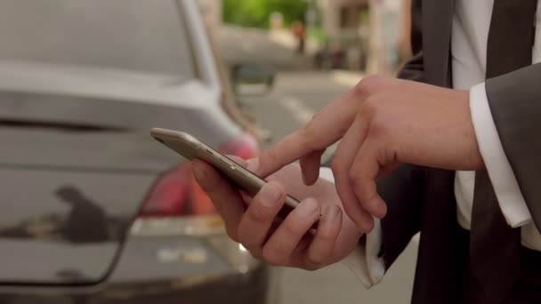 Людина вивчає інформацію на мобільному телефоні на тлі автомобіля — стокове відео