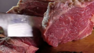 Bir ahşap tahta üzerinde ham sığır eti biftek kesmek