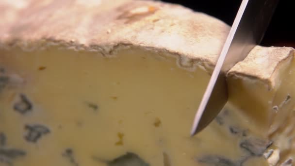 Yanan bir şömine arka plan üzerinde mavi peynir kesti — Stok video