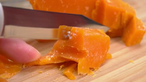 Mimolette queso cortado con cuchillo de queso en una tabla de bambú — Vídeo de stock