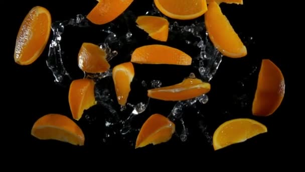 Кусочки апельсина с водой летят к камере — стоковое видео