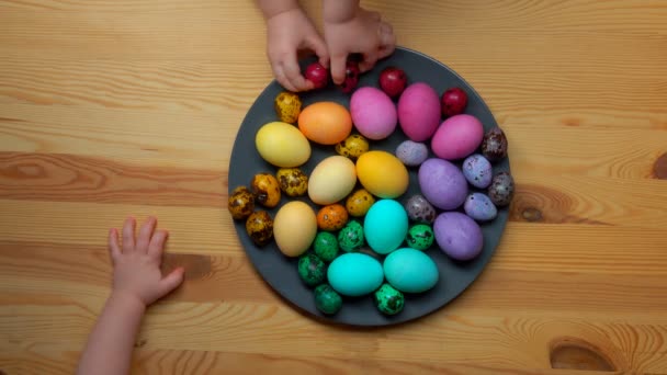 Gyermek kezébe veszi egy tányér színes húsvéti tojás — Stock videók