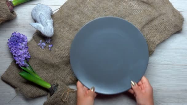 Hands put on a plate Easter nest with colored eggs — Stock Video
