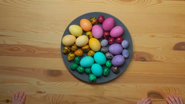 Timelapse de manos de niños tomando huevos de Pascua multicolores de un plato — Vídeo de stock