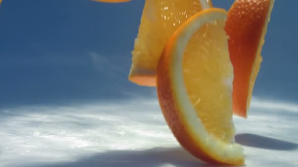 Rodajas de naranja caen sobre la mesa blanca — Vídeos de Stock