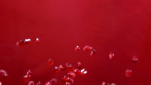 Rote reife Granatkerne fliegen auf rotem Hintergrund — Stockvideo