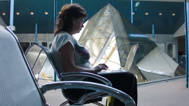 Mulher trabalhando em um laptop no aeroporto — Vídeo de Stock