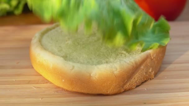 Chef pone hoja de lechuga en un bollo — Vídeos de Stock