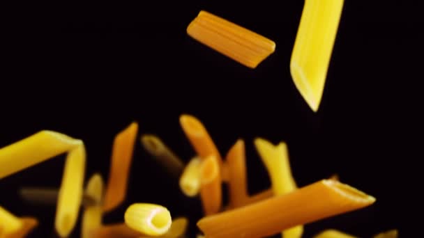 Colored pasta falling on a black background — Stock Video