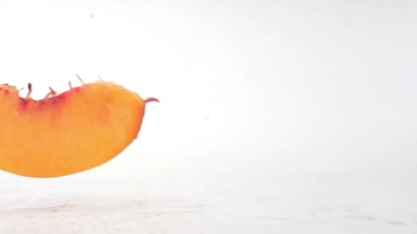 Pfirsichscheiben fallen auf eine nasse Oberfläche — Stockvideo