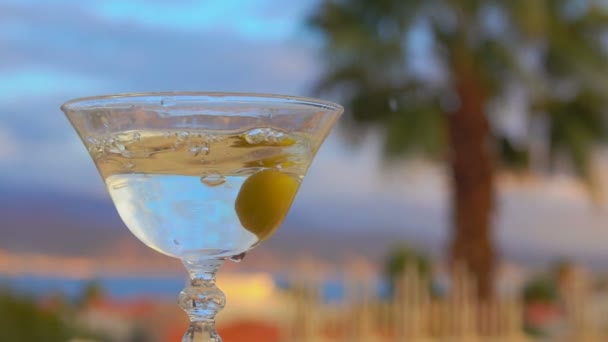 Olive falls into a glass with martini — Stock Video