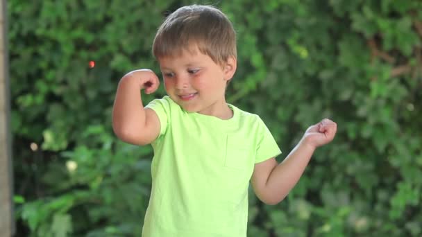 Pequeño niño muestra sus músculos — Vídeo de stock