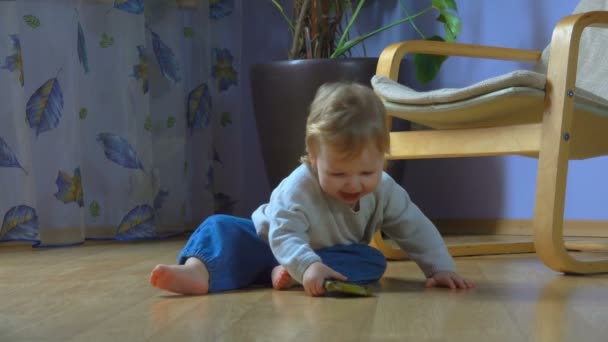 Чудесный голубоглазый ребенок сидит на полу и разговаривает по мобильному телефону — стоковое видео