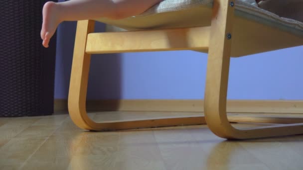 Босоногий ребенок спускается с кресла и идет — стоковое видео