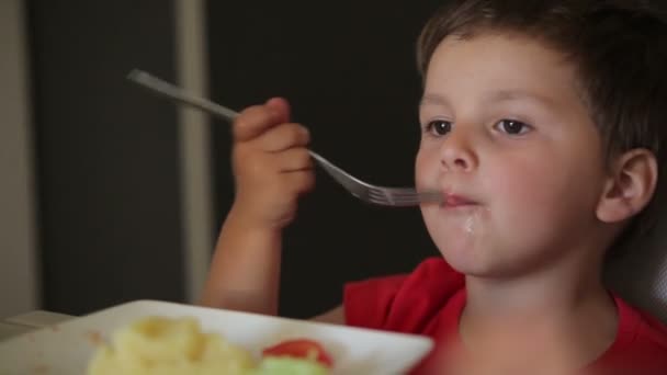 Menino está comendo salsicha grelhada com batatas — Vídeo de Stock