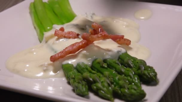 Gotas de jamón salteado sobre espárragos con salsa de queso — Vídeo de stock