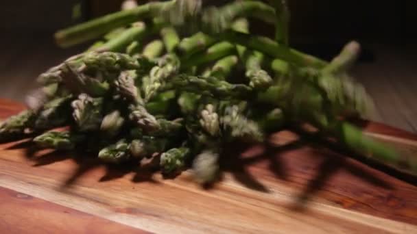 Espargos verdes frescos cai em uma tábua de madeira — Vídeo de Stock