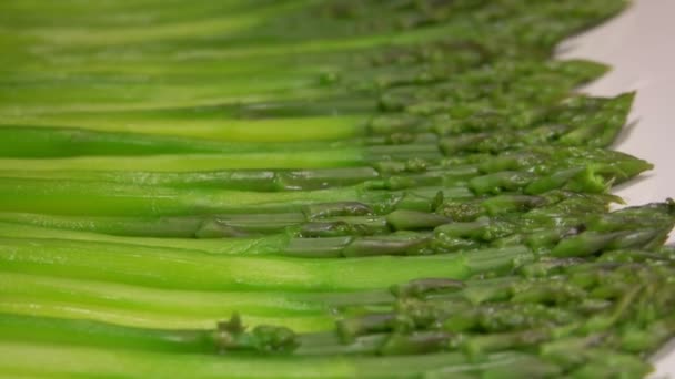 Boiled green asparagus lying on long white plate — Stock Video