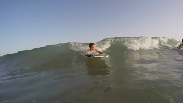 Niño surfea en una gran ola en la tabla de natación — Vídeos de Stock