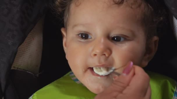 Curly brown-eyed toddler boy eating a porridge — Stock Video