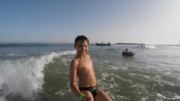 Chico salta de nuevo en la ola levantando spray de agua — Vídeo de stock