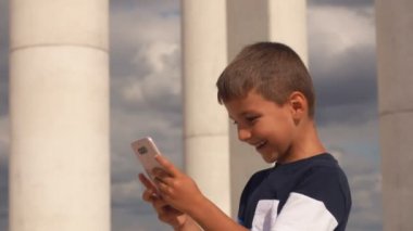 Mutlu gülümseyen çocuk cep telefonu ekranına bakıyor.