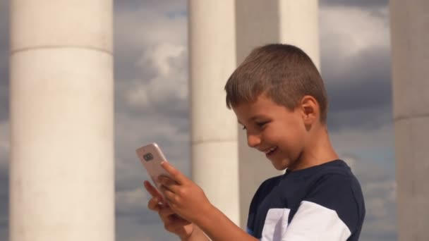 Happy smiling boy looks at screen of mobile phone — ストック動画