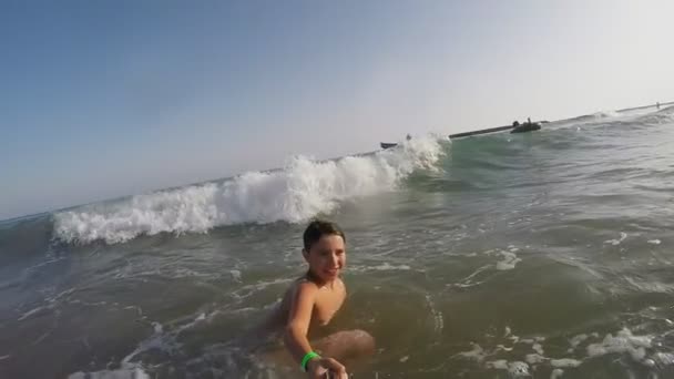 High splashing wave rolls over a cheerful boy — ストック動画