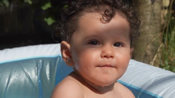 Kleine krullende jongen lachend en spetterend in het water — Stockvideo