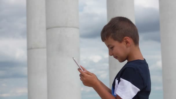 Chłopak drukuje wiadomość na telefonie komórkowym i uśmiecha się — Wideo stockowe