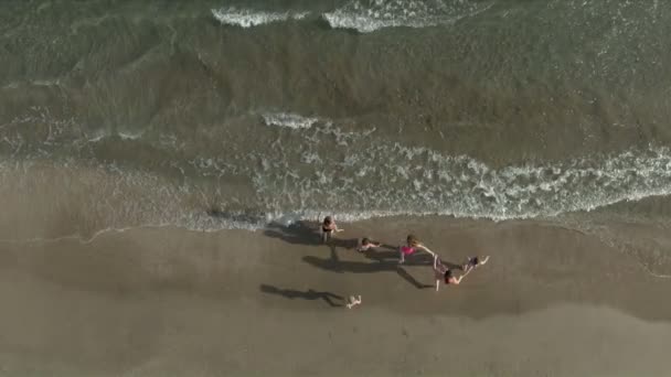 Strzał z powietrza dzieciaków trzymających się za ręce i wpadających do morza — Wideo stockowe