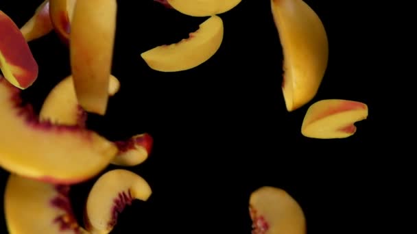 Pfirsichscheiben fliegen auf schwarzem Hintergrund herunter — Stockvideo