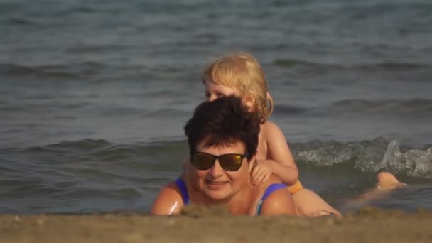 Mãe brinca com a menina loira na praia — Vídeo de Stock