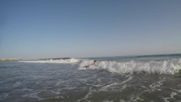 Yüzme tahtasındaki çocuk su sıçratan bir dalgada sörf yapıyor — Stok video