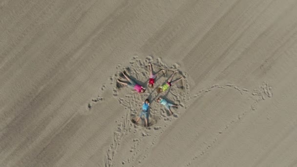 Aerial shot of children waving hands on the sand — Stock Video