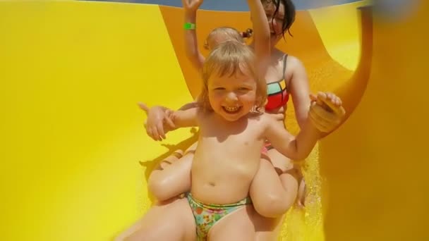 Mom with two girls ride down the orange slide — Stock Video