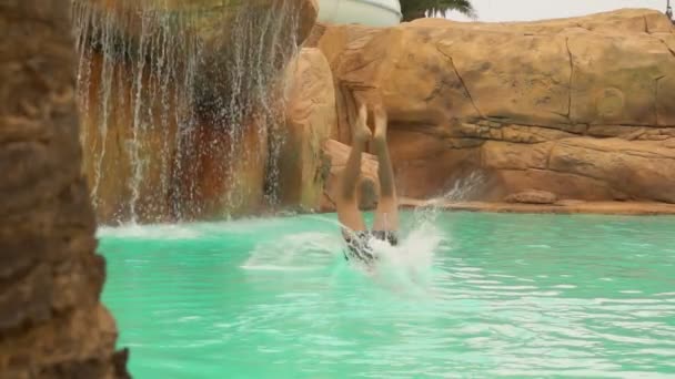 Young attractive man dives into pool in water park — Stock Video