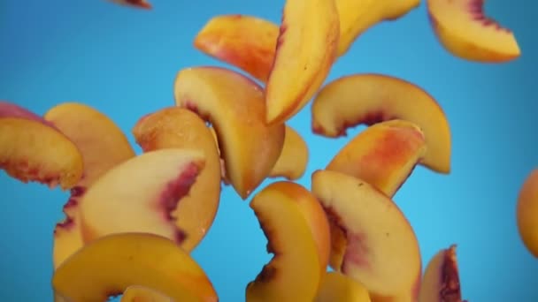 Pfirsichscheiben prallen auf blauem Hintergrund ab — Stockvideo