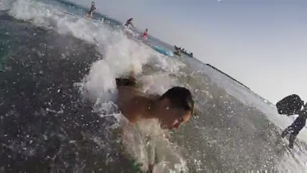 Sonriente niño en una tabla de natación surfea en la ola — Vídeos de Stock