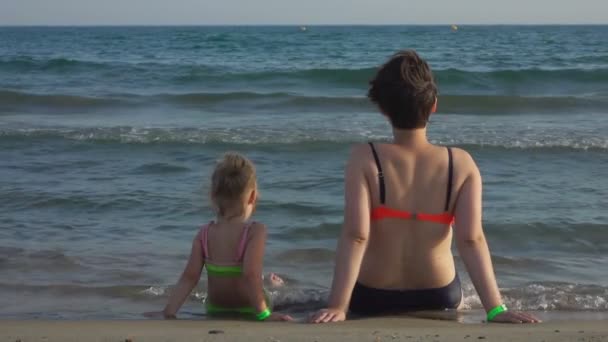 Μαμά και κόρη κάθονται στην παραλία. — Αρχείο Βίντεο
