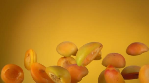 Sappige abrikozenhelften stuiteren op gele achtergrond — Stockvideo