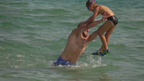 El hombre arroja al niño al agua de mar con salpicaduras — Vídeos de Stock