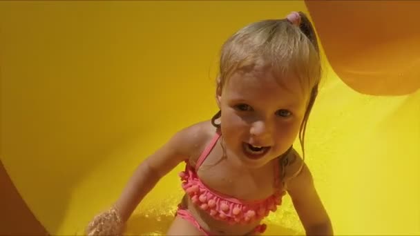 Engraçado menina cavalga para baixo slide em um parque aquático — Vídeo de Stock