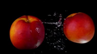 Şeftaliler çarpışıyor. Siyah zeminde su sıçrıyor.