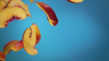 Şeftali dilimleri mavi arka planda uçar