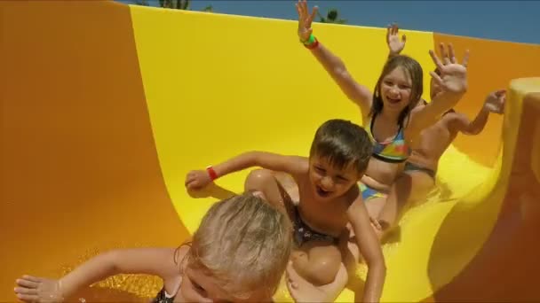 Kinderen rijden van sinaasappelglijbaan in een waterpark — Stockvideo