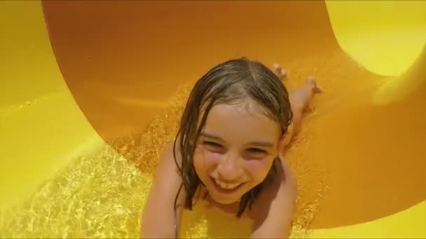 Смішна дівчина їде на помаранчевому слайді на животі — стокове відео