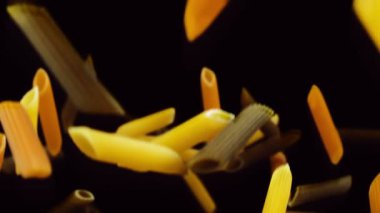 Siyah arka planda renkli makarna uçuyor.