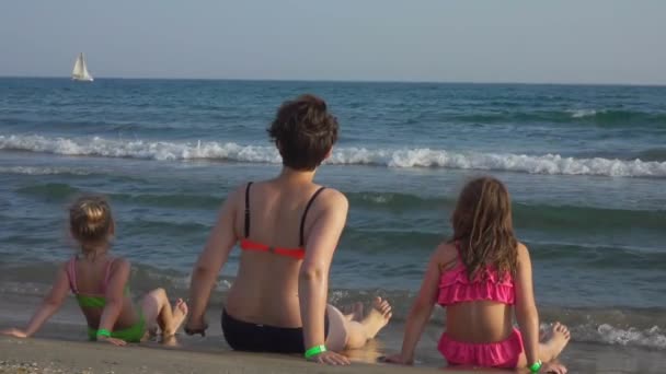 Mãe com duas meninas em trajes de banho senta-se na praia — Vídeo de Stock